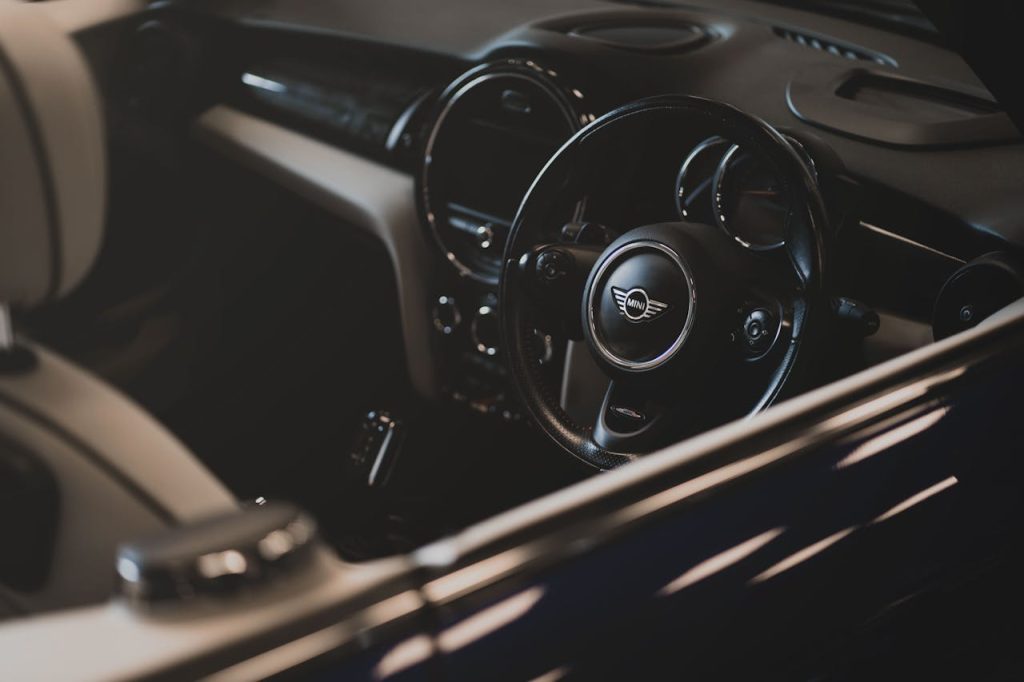 A stylish Mini Cooper car interior shot showcasing the steering wheel and dash in a low-light setting.